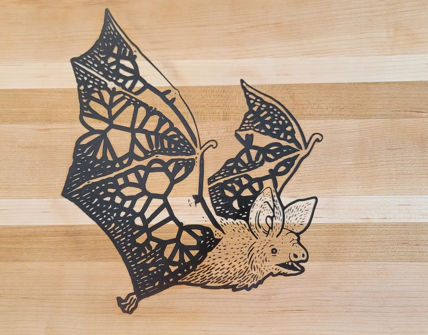 Finished light wood board carved with a bat in flight, its wings a pattern of small cells